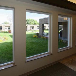 A hallway with large windows overlooking a garden area outside.