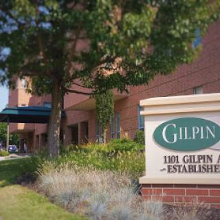 An outdoor view of a building with a sign reading 'Gilpin, Established' surrounded by trees and landscaping.