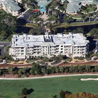 An aerial view of a residential building situated near a golf course and surrounded by landscaped greenery.