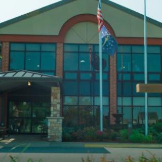 A modern building with large glass windows and flags at the entrance.