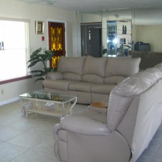 A cozy living room with a comfortable sofa and a glass coffee table in front of a large mirror.
