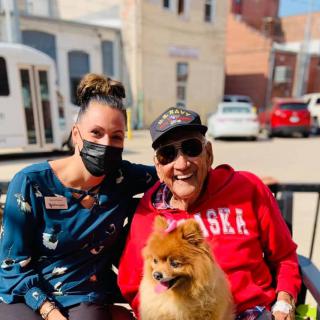 Two people and a dog enjoying a sunny day outside.