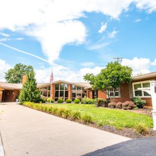A beautiful residential building surrounded by greenery and a clear blue sky.