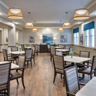 A modern dining area with neatly arranged tables and chairs, warm lighting, and stylish decor.