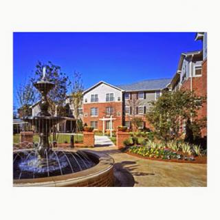 A beautiful residential area featuring a fountain and well-maintained gardens under a clear blue sky.