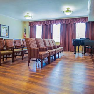A well-arranged conference room with chairs and a grand piano on a wooden floor.