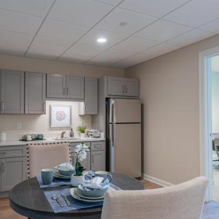 A modern kitchen and dining area featuring a table set for a meal, with subtle lighting and neutral tones.