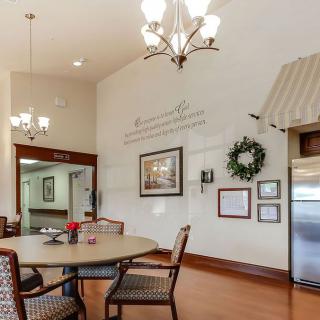A cozy dining area with a round table, elegant chandelier lighting, and decorative wall art.