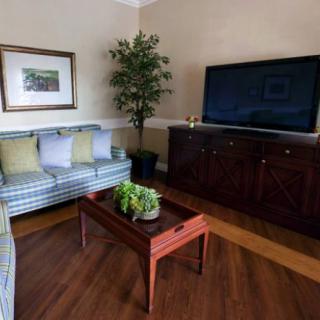 A cozy living room with a striped sofa, wooden coffee table, and a large television.