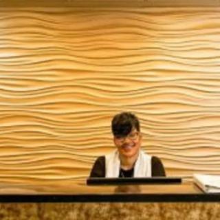 A receptionist working at a desk with a wave-patterned wall in the background.