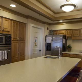 A modern kitchen with wooden cabinets, stainless steel appliances, and a large central island.