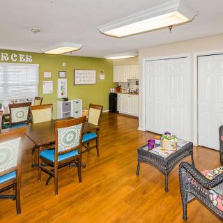 A well-lit interior room with tables, chairs, and a kitchenette.