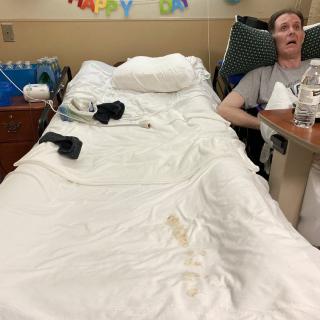 A patient lying in a hospital bed with medical equipment nearby.