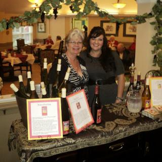 Two women showcasing a variety of wines at an event in a restaurant setting.