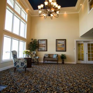 A spacious lobby with a large chandelier, patterned carpet, and decorative artwork on the walls.