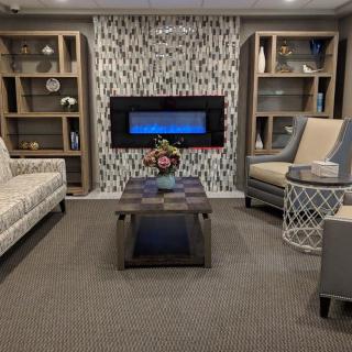 A cozy living room with a modern fireplace, stylish furniture, and decorative bookshelves.