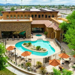 An outdoor swimming pool at a resort, surrounded by trees and umbrellas.