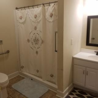 A clean and well-lit bathroom with a shower, sink, and toilet.
