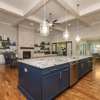 A modern kitchen with a large island and pendant lighting, featuring a spacious open floor plan.