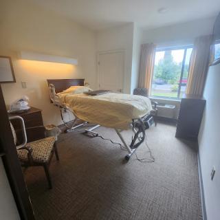 A comfortable hospital patient room featuring a bed and a chair by the window.