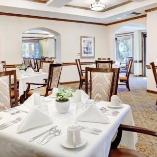 An elegant dining room with neatly arranged tables and chairs, featuring a formal table setting with white tablecloths.
