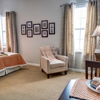 A cozy bedroom with a comfortable armchair, neatly made bed, and decorative elements.