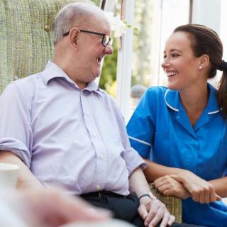 A nurse and an elderly man share a warm conversation, highlighting compassionate healthcare.