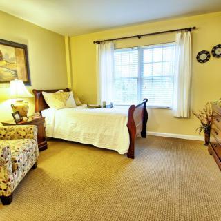 A cozy bedroom featuring a single bed, traditional decor, and a window with curtains.