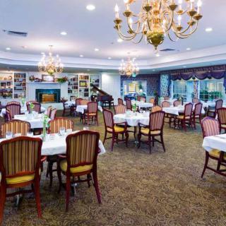 An elegant restaurant dining area with neatly arranged tables and chairs under ornate chandeliers.