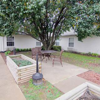 A cozy outdoor patio area with seating surrounded by lush greenery.