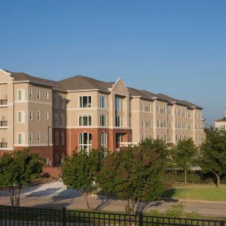 A multi-story residential apartment complex surrounded by trees.