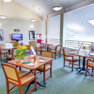 A cozy dining area with neatly arranged tables and chairs, adorned with decorative items and warm lighting.