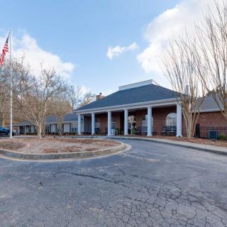 A brick building with a covered entrance and an American flag on display, surrounded by trees.