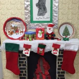 A festive fireplace decorated for Christmas with stockings, Santa Claus figures, and holiday-themed plates.