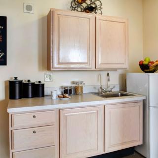 A small kitchen space with light wood cabinets and a compact refrigerator.