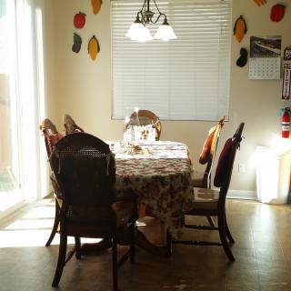 A cozy dining room with a table set for four, sunlight streaming through the window.