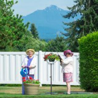 Two people tending to a garden with mountains in the background.