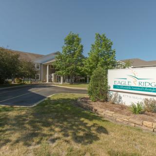 A landscaped driveway leading to a building entrance with a sign nearby.