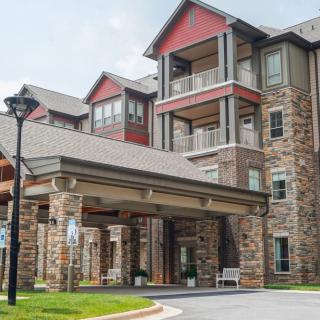 A multi-story residential building with a stone facade and covered entrance.