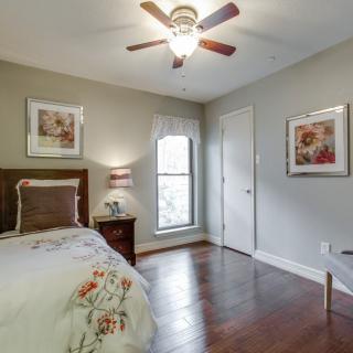A cozy bedroom with a single bed, adorned with decorative pillows and art on the walls, featuring a ceiling fan and a window for natural light.