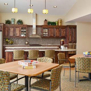 A modern kitchen and dining area with wooden cabinets, bar stools, and overhead lighting.