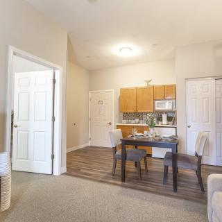 A view of a cozy apartment featuring an open kitchen and dining area with wooden furniture.