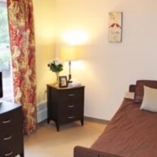 A cozy bedroom with a bed, nightstands, and a lamp providing warm lighting.