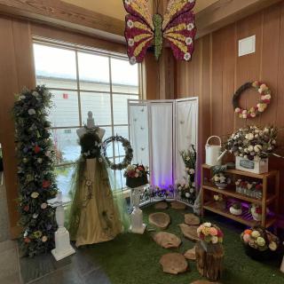 A beautifully arranged indoor display featuring floral decor, a large butterfly, and wooden accents.