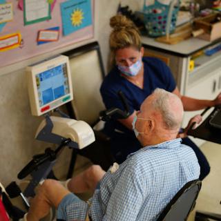 A nurse assists an elderly patient with medical monitoring in a healthcare setting.
