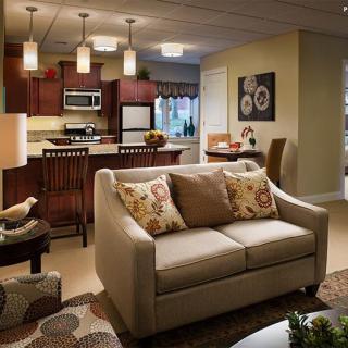 A cozy living room with an open floor plan leads into a modern kitchen, featuring elegant decor and soft lighting.