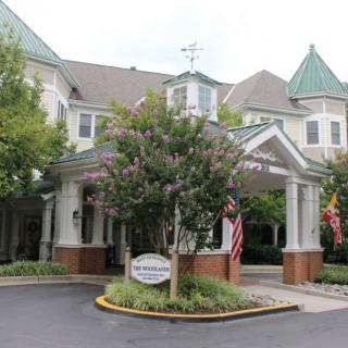 A well-landscaped entrance of a large building with flags and trees.
