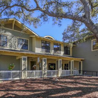 A two-story house with a large tree in the yard.