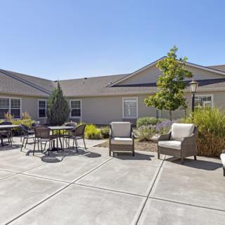 A sunny courtyard featuring outdoor seating and landscaping.