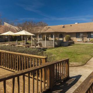 A sunny backyard with a wooden fence and covered patio area.
